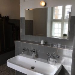 Montering af spejl på badeværelse med grå fliser over vask