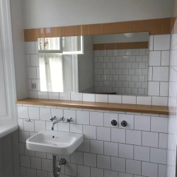 Montering af spejl på hvidt badeværelse