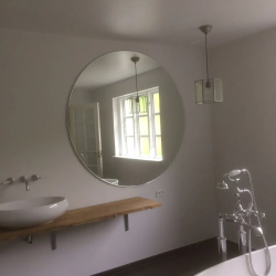 Rundt spejl monteret af glarmester på hvidt badeværelse