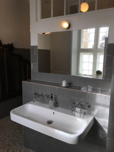 Montering af spejl på badeværelse med grå fliser over vask