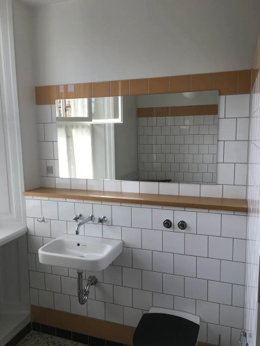 Montering af spejl på hvidt badeværelse