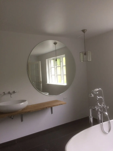 Rundt spejl monteret af glarmester på hvidt badeværelse